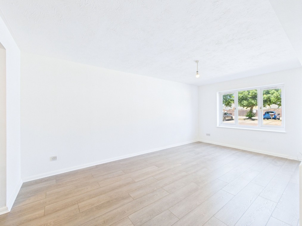 Bright and spacious living room in a recently decorated ground floor flat at Archers Court, featuring large windows, modern light fixture, and wooden flooring.