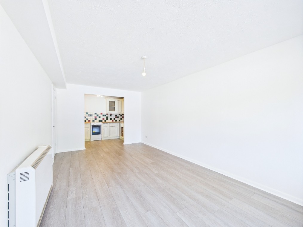 Bright and spacious ground floor flat interior at Archers Court, featuring modern kitchen with stylish units, light wooden flooring, and freshly painted white walls.