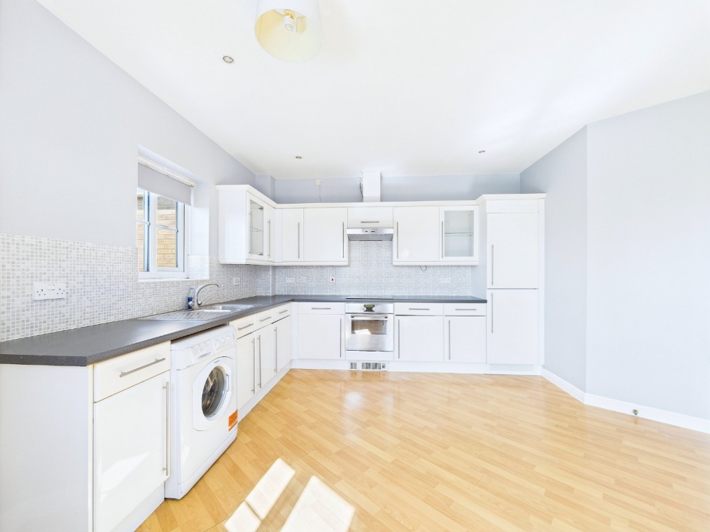 Bright and modern kitchen in a two-bedroom flat on Coniston Avenue, featuring white cabinetry, stainless steel appliances, and wooden flooring, ideal for first-time buyers or investors.